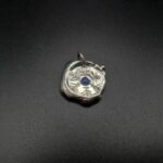 Médaillon rond façon pièce ancienne, en argent et saphir